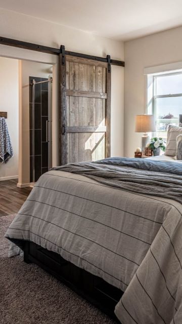 a manufactured home master bedroom featuring a barn-door entrance to the master bath