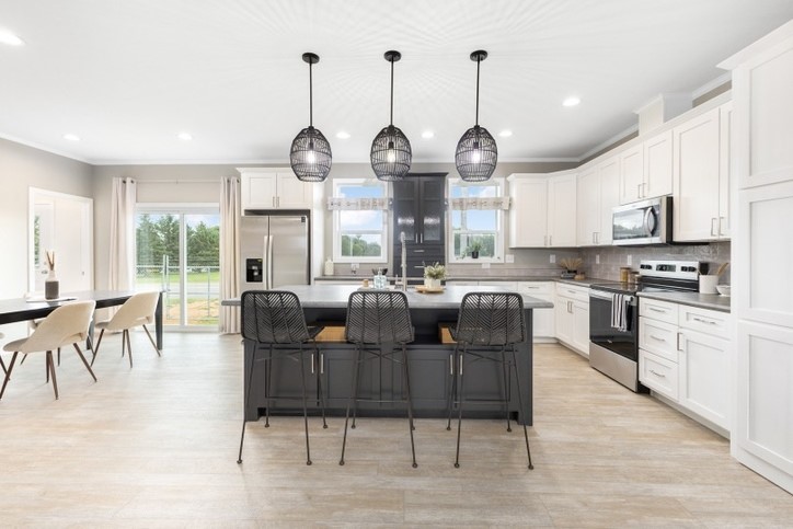 Luxurious and modern view of the Cavco Sapphire kitchen with a roomy island, pendant lighting and a sliding glass door.