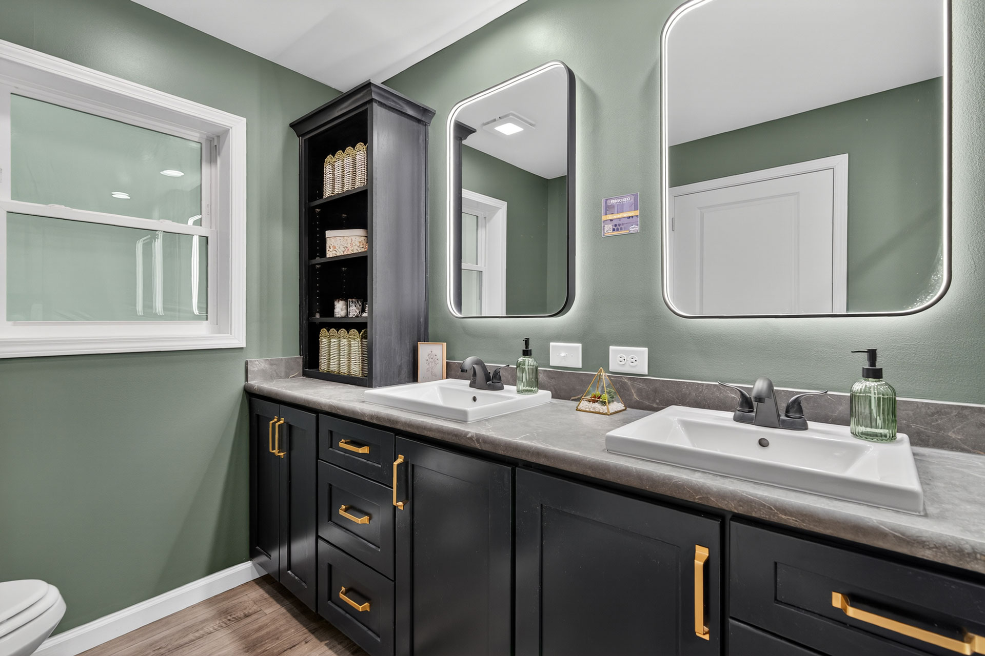 View of the primary bath in the Signature Francisco modular home, offering his-and-hers sinks with vanity, LED lighting, walk-in shower and functional storage options and shelving.