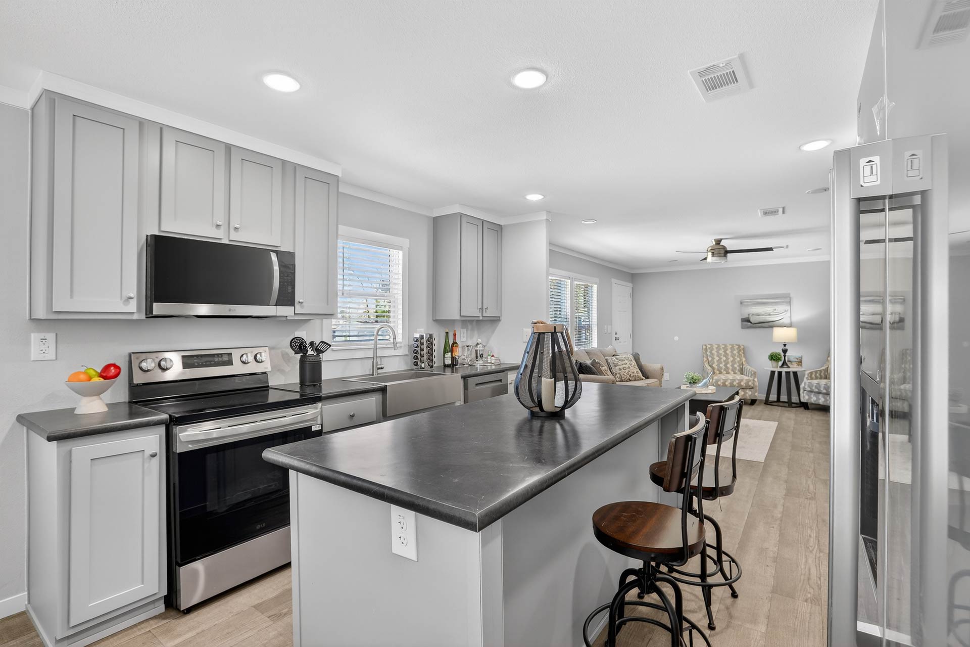 Open-concept living room and kitchen inside the Cavco Momentum manufactured home featuring a large kitchen island and modern finishes.
